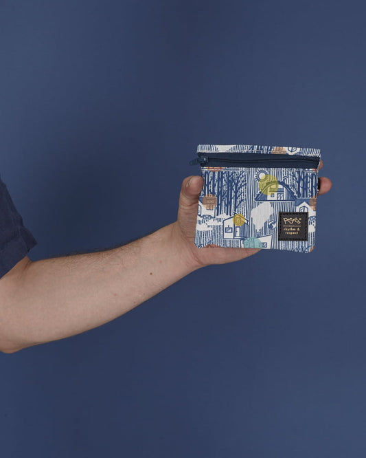 peSeta-PET-cartera-pequena-tinyhouse, cartera multifuncional pequeña pero ultra versatil, estampado super original de una casa en un bosque en tonos azules, con cierre y correa azul, moda lentita, moda española.