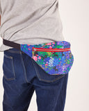 bolso-riñonera nuria flores con cierre delantero, cinta regulable, estampado original de flores sobre un fondo azul, moda lentita, moda española, marca unisex